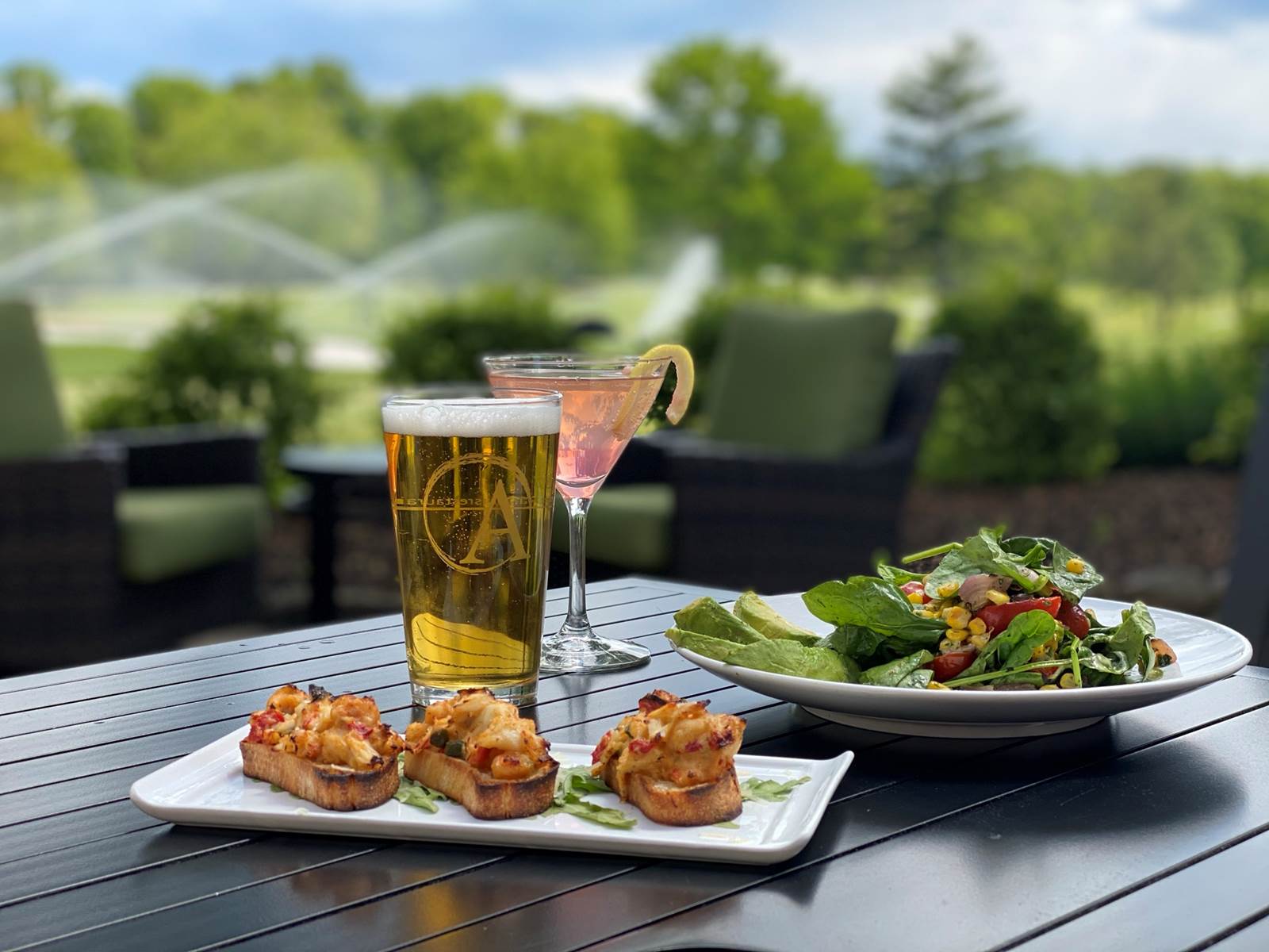 A photo of cocktails and food against a lovely golf course setting
